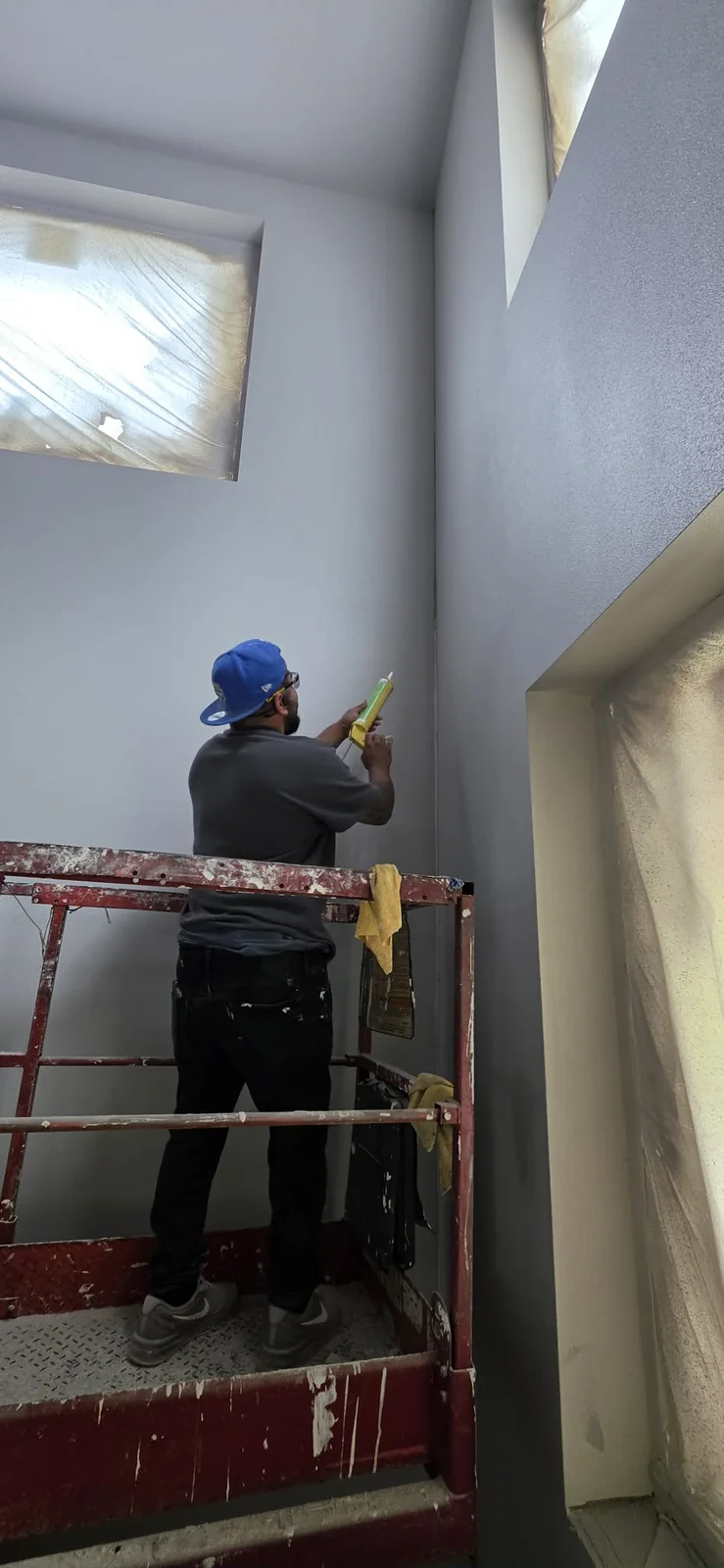 Solis Interiors worker on a scissor lift inside a large open room.