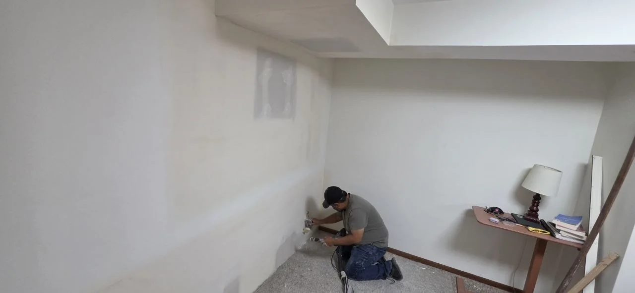 Solis Interiors worker kneeling beside the lower edge of an interior wall.